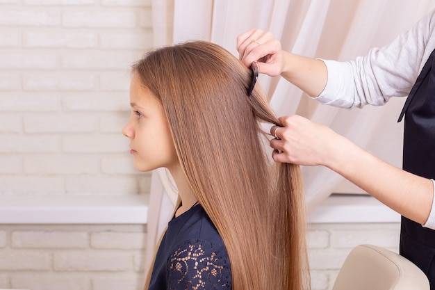 Mani del parrucchiere che spazzolano i capelli della bambina