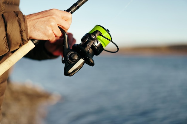 Mani del pescatore che tengono la canna da pesca da vicino