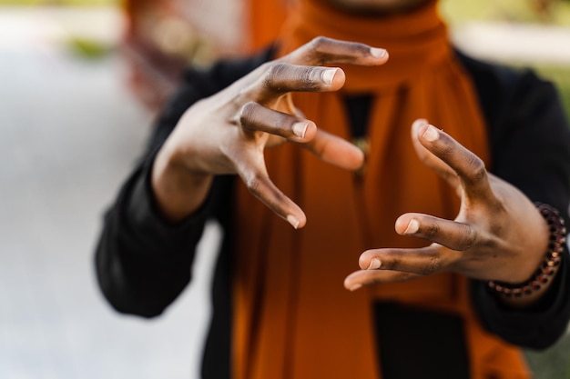 Mani del primo piano della donna musulmana nera alla meditazione cinese del qigong e all'allenamento sportivo all'aperto La ragazza africana sta meditando all'aperto vicino al pergolato cinese