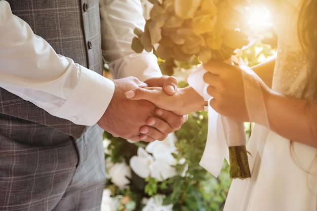 Mani del primo piano della sposa e dello sposo della fidanzata durante la registrazione del matrimonio il giorno del matrimonio della cerimonia