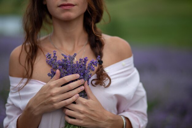 Mani del primo piano di bella ragazza che tengono il mazzo di fiori di lavanda