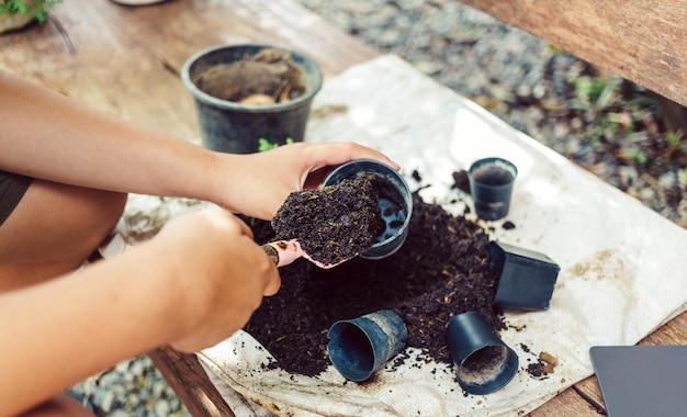 Mani del ragazzo che spalano il terreno in vasi per preparare le piante per piantare il concetto di attività ricreative