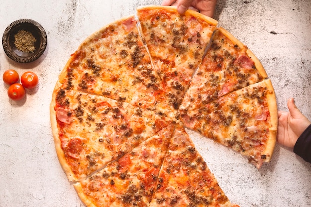 Mani del ragazzo e dell'uomo che prendono una fetta di pizza, primo piano. Padre e figlio che mangiano