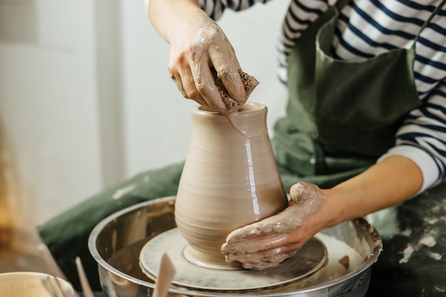 Mani del vasaio che fanno vaso di terracotta sul tornio da vasaio. Ceramiche e ceramiche nei laboratori.