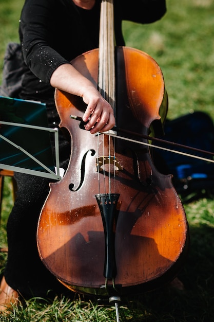 Mani del violoncellista Violoncellista che suona il violoncello sullo sfondo del campo Concetto di arte musicale passione nella musica Performance sulla natura Primo piano di strumenti musicali Profondità ridotta in stile vintage