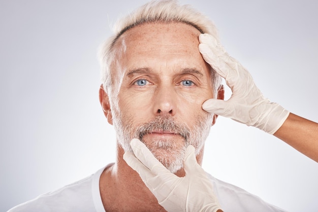 Mani del viso dell'uomo o guanti di chirurgia estetica sullo sfondo dello studio per la dermatologia medica del collagene per la cura della pelle o la toelettatura anti invecchiamento Chirurgo plastico ritratto o controllo del paziente maturo per il cambiamento facciale