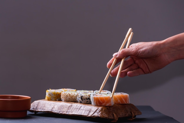 Mani delicate con le bacchette che estraggono il sushi da un vassoio
