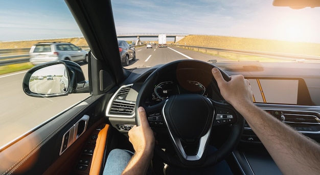 Mani dell'automobilista sul viaggio su strada del volante che guida su strada autostradale