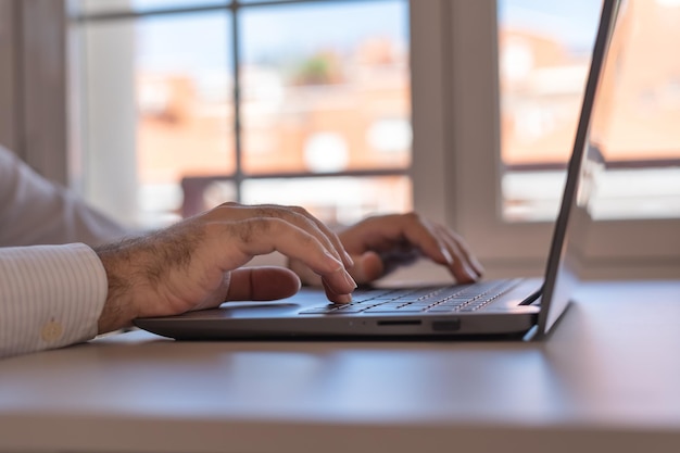 Mani dell'uomo che digitano una tastiera portatile a casa telelavoro