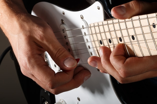 Mani dell'uomo che gioca il primo piano della chitarra elettrica