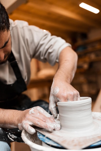 Mani dell'uomo che lavorano al tornio e fanno una pentola