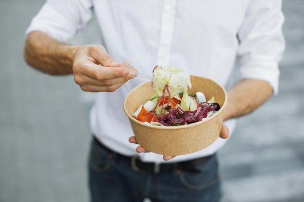 Mani dell'uomo che mangia pranzo sano all'aperto