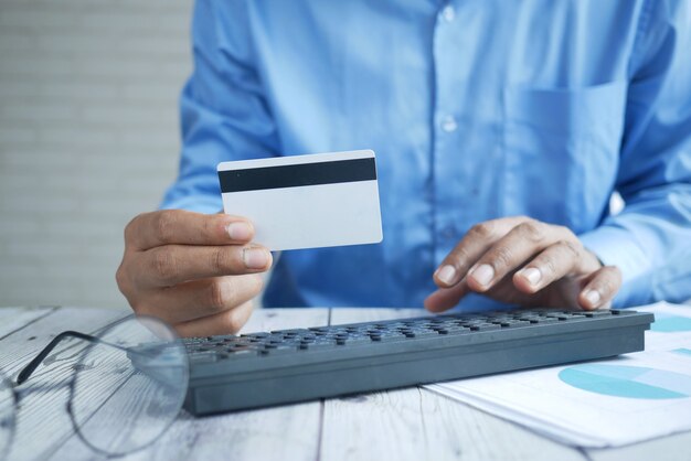 Mani dell'uomo che tengono la carta di credito e usano il laptop per fare acquisti online