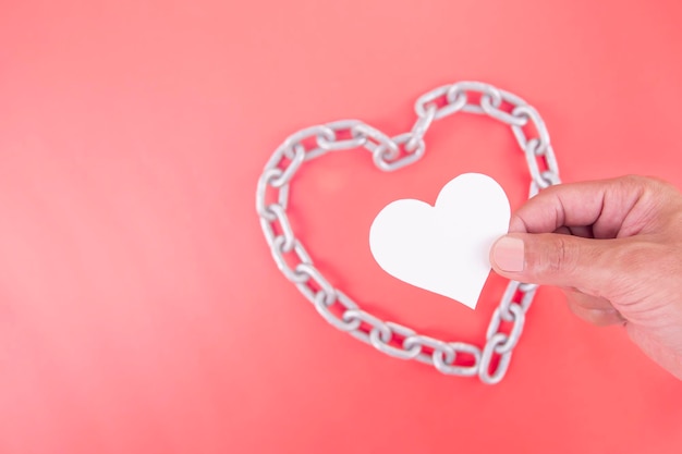 Mani dell'uomo che tengono un cuore bianco all'interno di una catena di ferro responsabilità di protezione della salute del cuore CSR