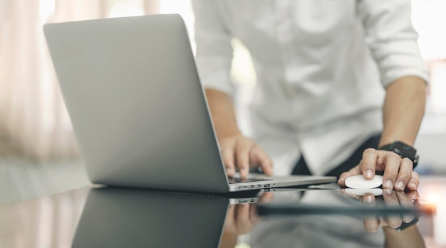 Mani dell'uomo del primo piano usando il mouse e il computer portatile