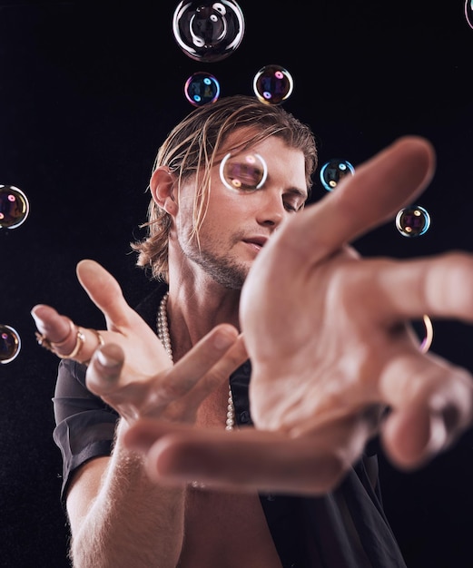 Mani dell'uomo e bolle in studio per performance di arte magica o spettacolo creativo su sfondo nero Modella artista e sapone con arcobaleno chiaro mistero estetico o presentazione teatrale sullo sfondo