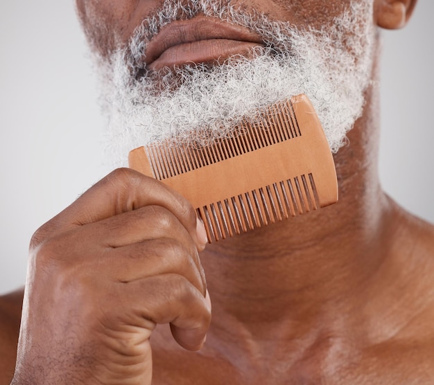 Mani dell'uomo e pettine sulla barba per curare la bellezza o l'igiene della cura della pelle su uno sfondo da studio