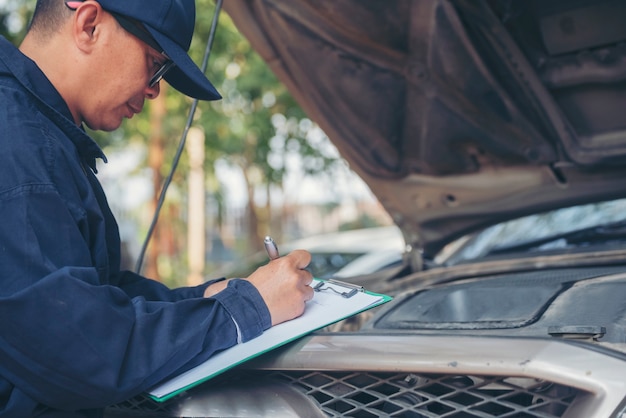 Mani dell'uomo meccanico che controllano pneumatici per auto all'aperto in loco servizio garage auto per centro automobilistico