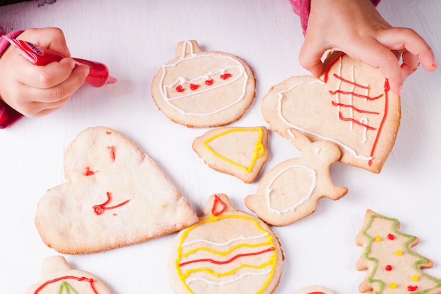 Mani della bambina, che disegna sui biscotti di pan di zenzero