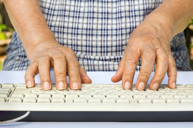 Mani della donna anziana sulla tastiera del computer