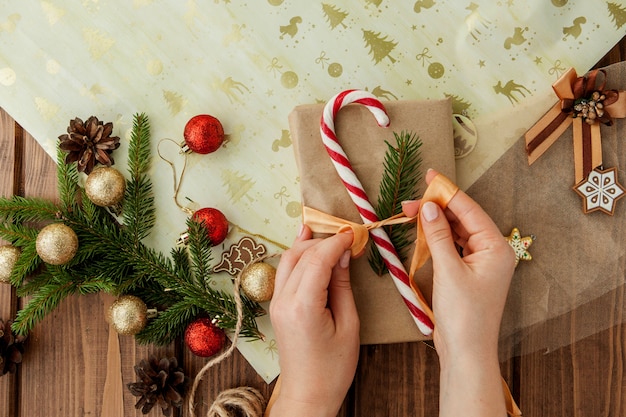 Mani della donna che avvolgono il regalo di Natale