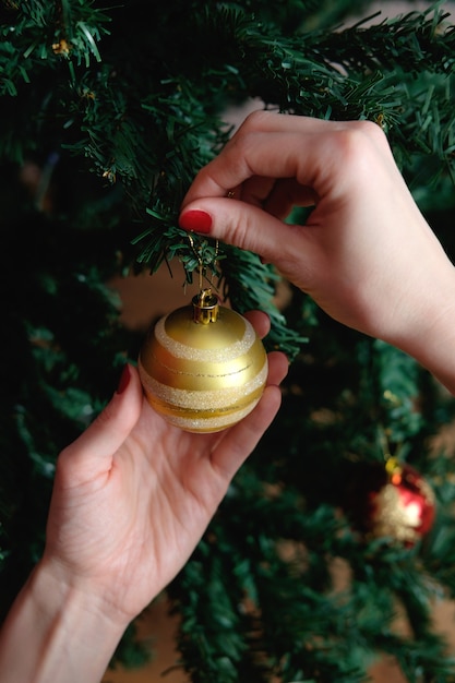 Mani della donna che decora l'albero di Natale