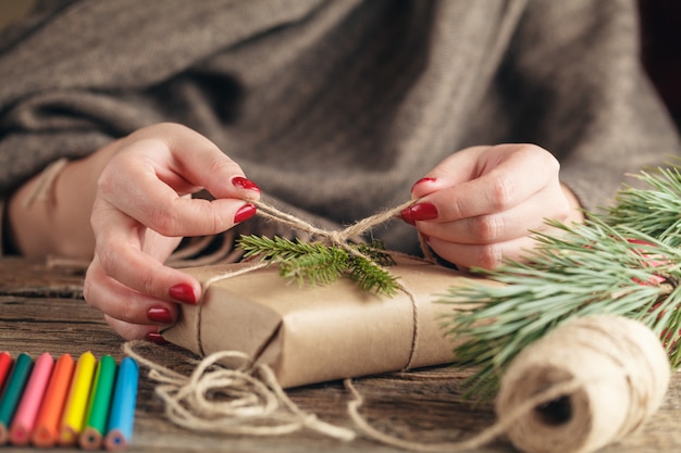 Mani della donna che decorano il contenitore di regalo di natale