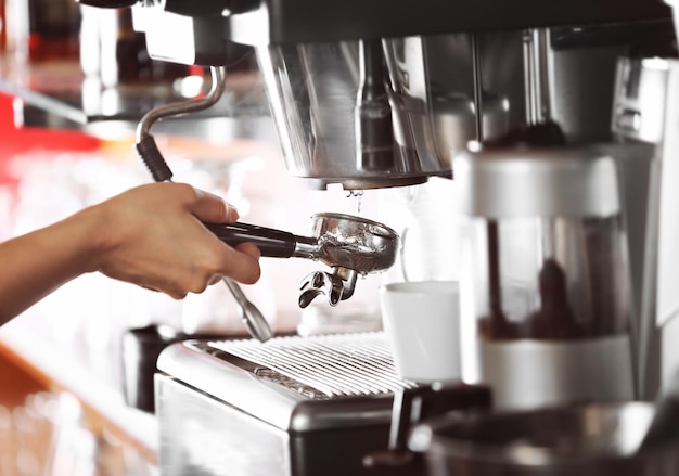 Mani della donna che fanno caffè espresso in caffè