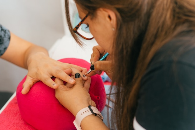 Mani della donna che fanno manicure in salone.