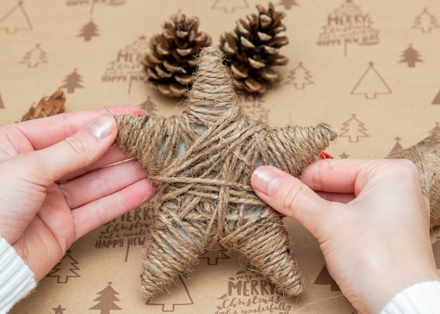 Mani della donna che fanno un ornamento di Natale