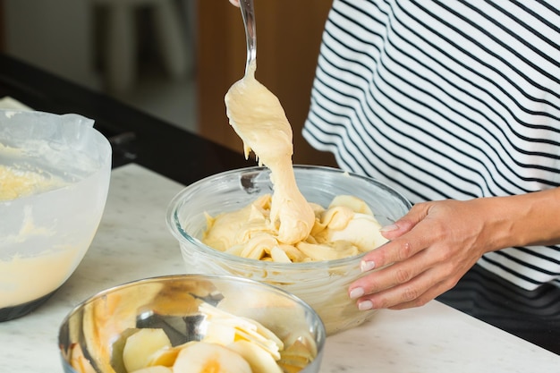 Mani della donna che mettono la pasta durante la cottura della torta di mele