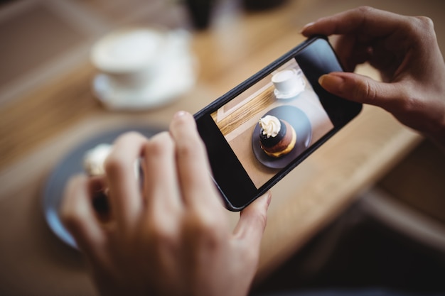 Mani della donna che prendono una foto di alimento dolce dal telefono cellulare