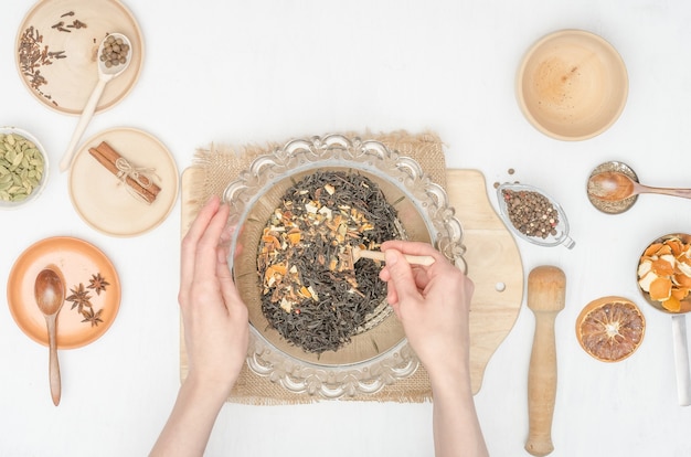 Mani della donna che preparano il tè indiano di masala con le spezie