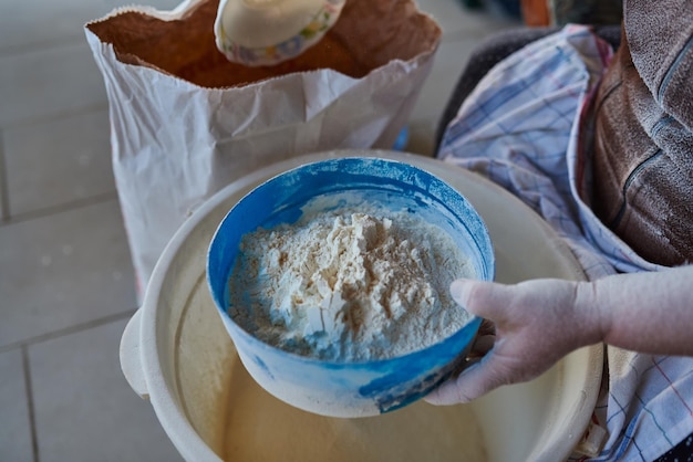 Mani della donna che setacciano la farina con il filtro per farina