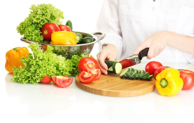 Mani della donna che tagliano le verdure sulla lavagna della cucina