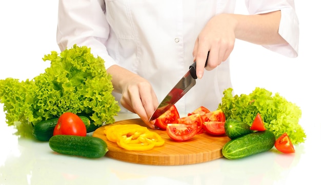 Mani della donna che tagliano le verdure sulla lavagna della cucina