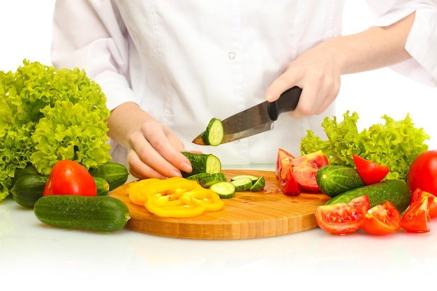 Mani della donna che tagliano le verdure sulla lavagna della cucina