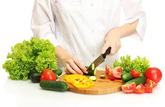 Mani della donna che tagliano le verdure sulla lavagna della cucina