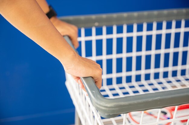 Mani della donna che tengono il nuovo carrello bianco vuoto