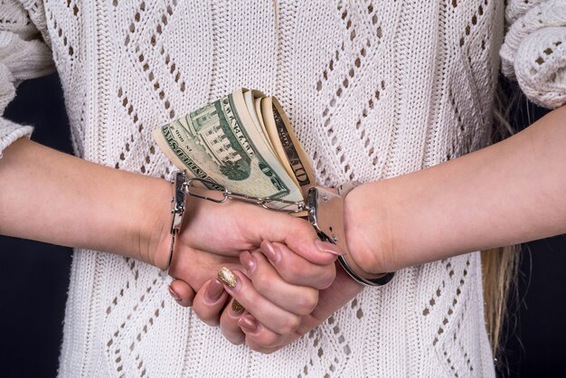 Mani della donna che tengono le banconote del dollaro in manette dietro la schiena