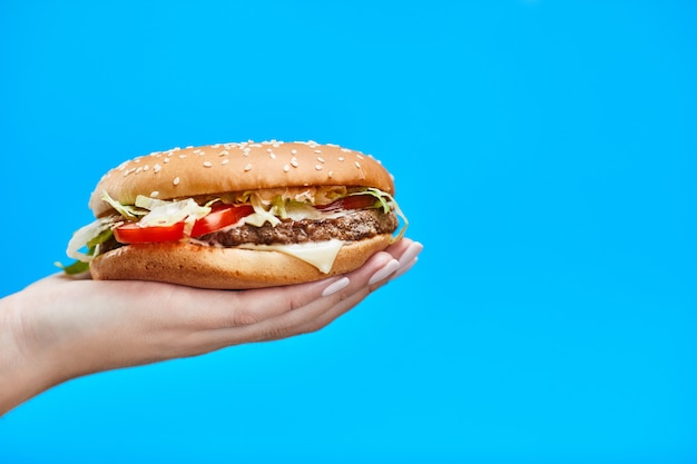 Mani della donna che tengono un hamburger