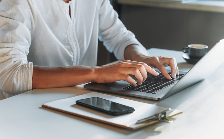 Foto mani della donna del primo piano che digitano sulla tastiera utilizzando il computer portatile mentre si lavora o si studia da casa. istruzione o lavoro online. concerto di lavoro a distanza