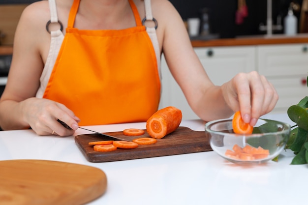Mani della donna del primo piano che tagliano le verdure del cetriolo dal coltello
