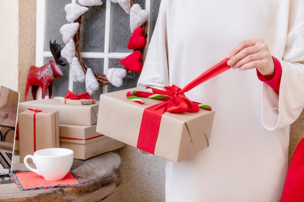 Mani della donna imballaggio Confezione regalo con nastro rosso alla vigilia delle vacanze di Natale e Capodanno.