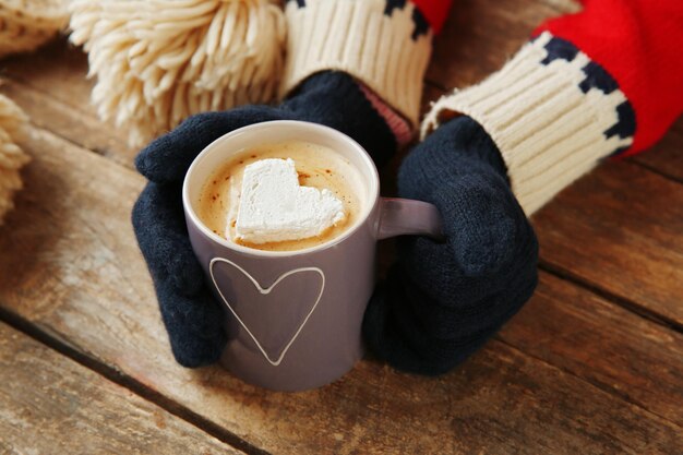 Mani della donna in guanti che tengono una tazza di caffè