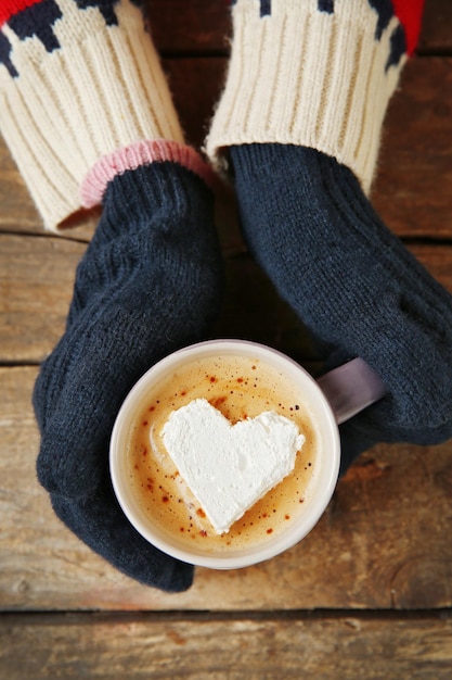 Mani della donna in guanti che tengono una tazza di caffè