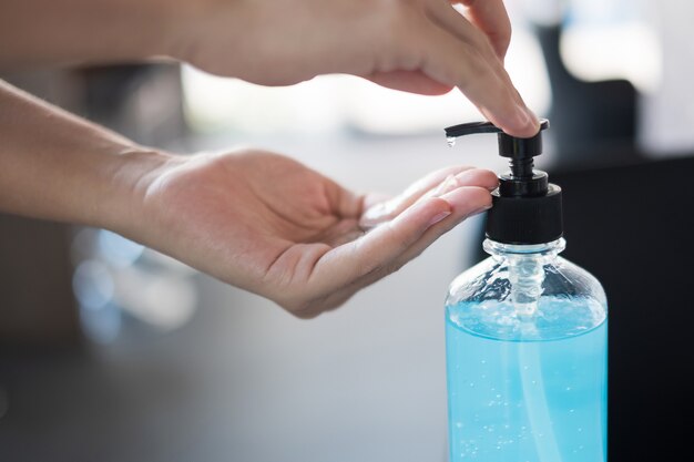 Mani della donna usando il distributore di gel disinfettante per mani