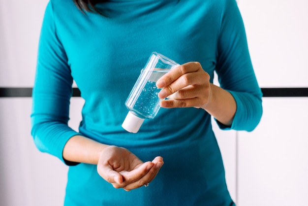 Mani della donna utilizzando gel disinfettante in bottiglia di plastica per la protezione del coronavirus dell'igiene delle mani in camera da letto