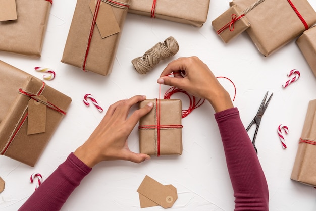 Mani della femmina che avvolgono i contenitori di regalo di Natale