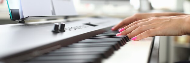 Mani della giovane donna suonare il pianoforte a casa